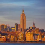 Zachód słońca nad Manhattanem. Widać Empire State Building i Chrysler Building. Zastanawiasz się, ile się leci do Nowego Jorku?