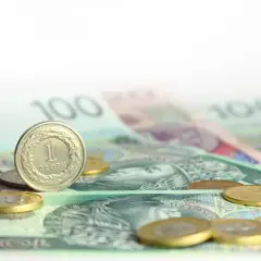Monety i banknoty 100 zł na białym tle.