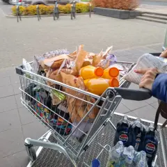 Pełny wózek zakupowy, w tym napoje i produkty spożywcze, sugeruje analizę cen w Wilnie.