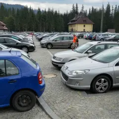 Duży parking samochodowy na Łysej Polanie na Słowacji, otoczony lasem.