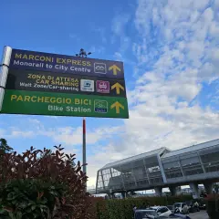 Znaki na lotnisku Bolonia wskazują drogę do Marconi Express, car sharingu i parkingu rowerowego.