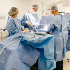 Zespół chirurgów w sterylnych strojach pracuje na bloku operacyjnym. To ich codzienność, za którą należy się dodatek za pracę na bloku operacyjnym.