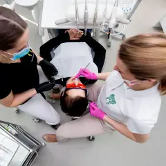 Dwie asystentki stomatologiczne pracują przy pacjencie. Zastanawiasz się, ile zarabia asystentka stomatologiczna?