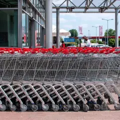 Rzędy wózków sklepowych z czerwonymi uchwytami przed francuskim hipermarketem.