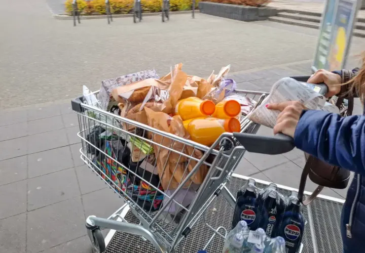 Pełny wózek zakupowy, w tym napoje i produkty spożywcze, sugeruje analizę cen w Wilnie.