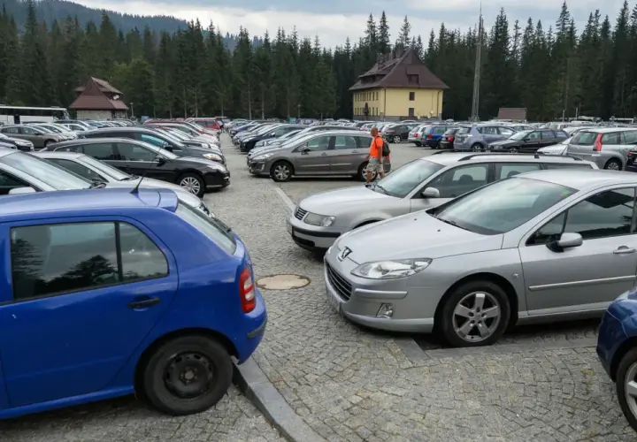 Duży parking samochodowy na Łysej Polanie na Słowacji, otoczony lasem.