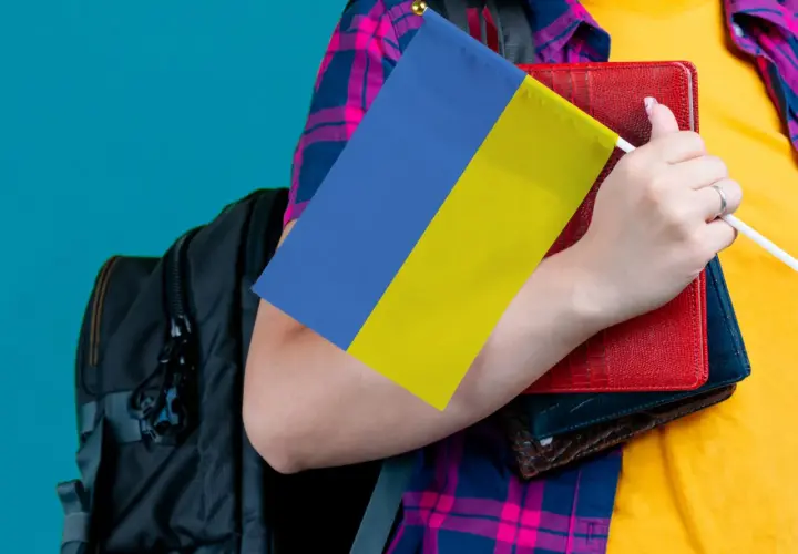 Osoba z plecakiem trzyma flagę Ukrainy i książki. Ceny we Lwowie mogą być różne, ale wiedza jest bezcenna.