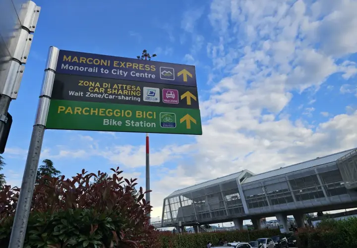 Znaki na lotnisku Bolonia wskazują drogę do Marconi Express, car sharingu i parkingu rowerowego.
