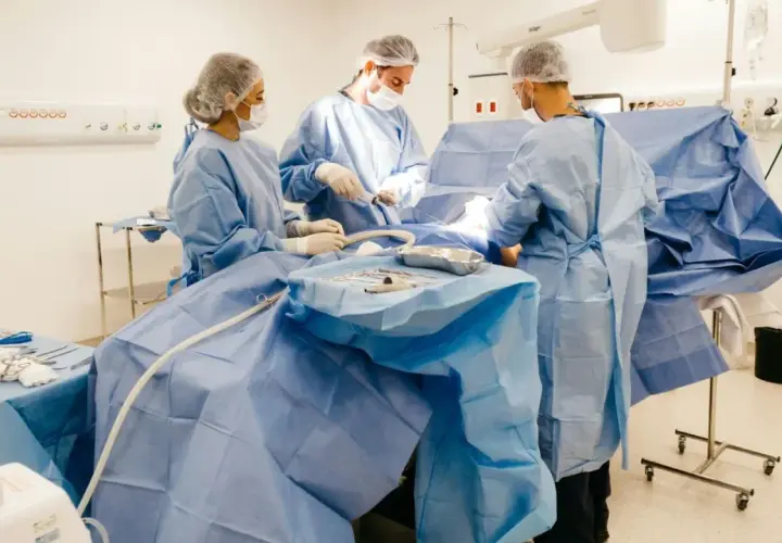 Zespół chirurgów w sterylnych strojach pracuje na bloku operacyjnym. To ich codzienność, za którą należy się dodatek za pracę na bloku operacyjnym.