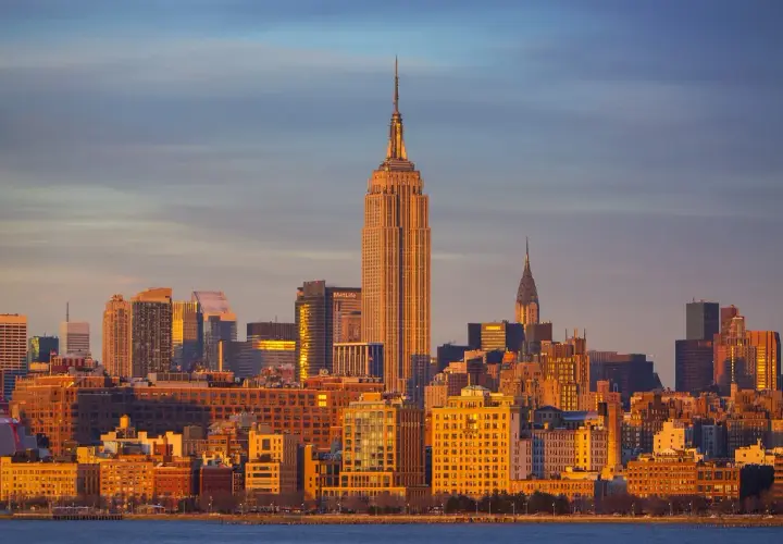 Zachód słońca nad Manhattanem. Widać Empire State Building i Chrysler Building. Zastanawiasz się, ile się leci do Nowego Jorku?