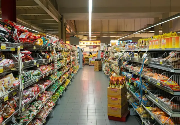 Długie alejki pełne kolorowych opakowań, typowe dla **Holandii sklepy** spożywcze. Widać mnóstwo przekąsek, słodyczy i produktów instant.