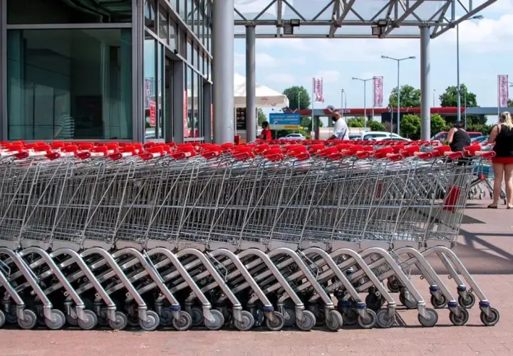 Rzędy wózków sklepowych z czerwonymi uchwytami przed francuskim hipermarketem.