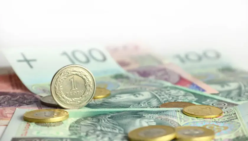 Monety i banknoty 100 zł na białym tle.
