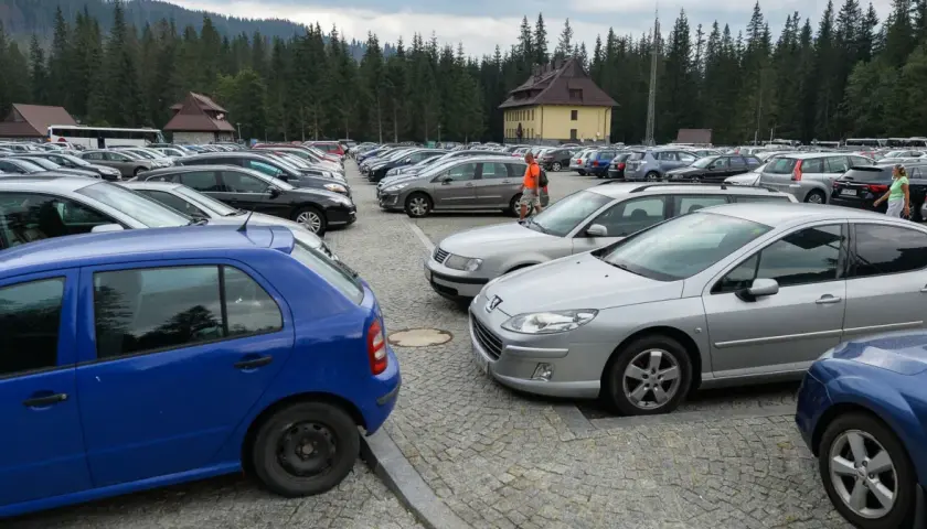Duży parking samochodowy na Łysej Polanie na Słowacji, otoczony lasem.