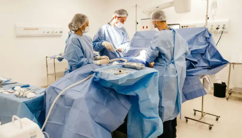 Zespół chirurgów w sterylnych strojach pracuje na bloku operacyjnym. To ich codzienność, za którą należy się dodatek za pracę na bloku operacyjnym.