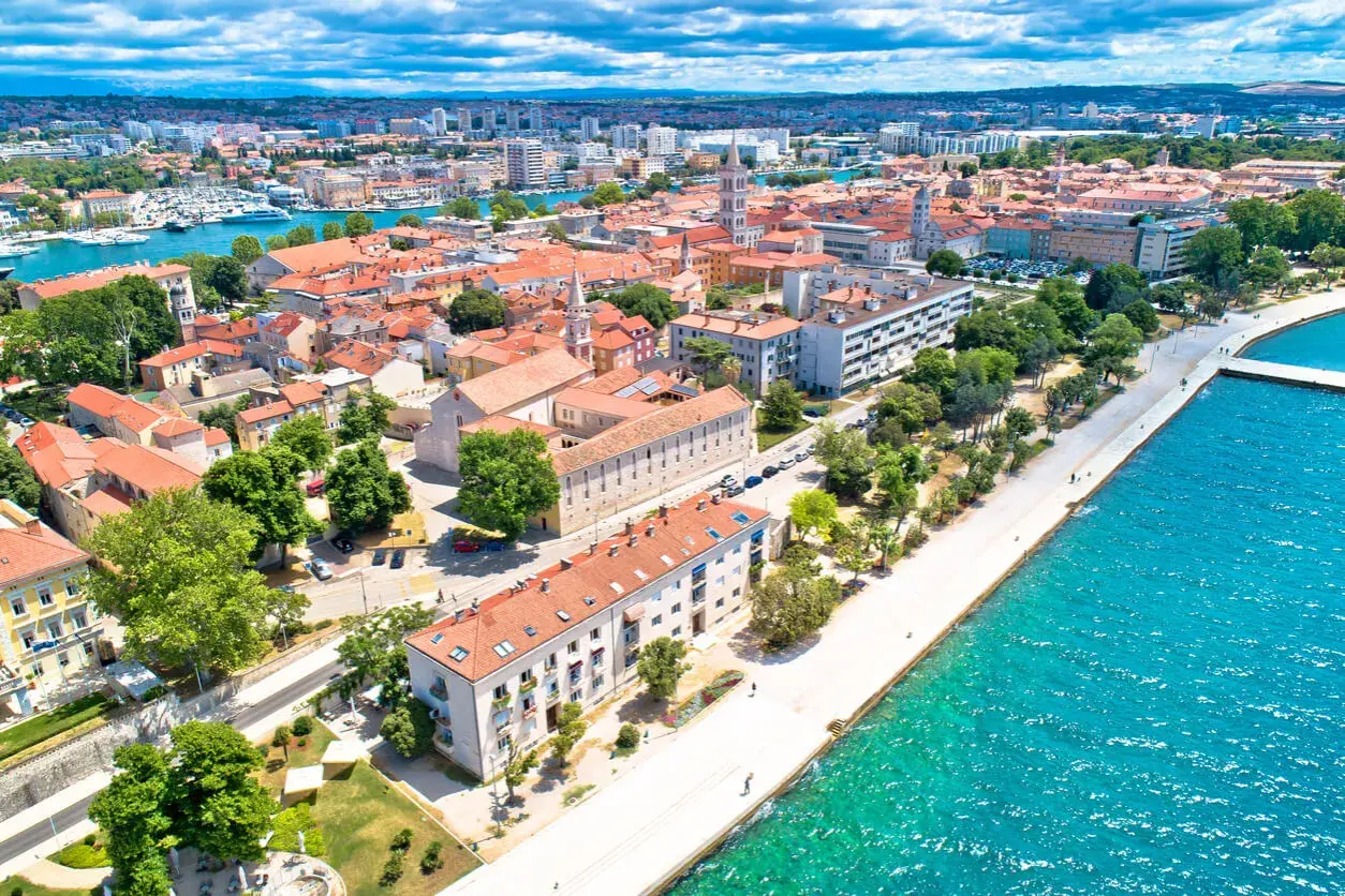 Widok na Zadar z lotu ptaka: czerwone dachy, turkusowe morze i nowoczesne budynki. Ceny w Zadarze zachęcają do odwiedzin.