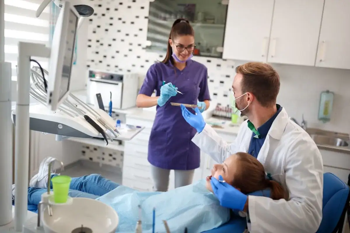 Lekarz i asystentka stomatologiczna pracują przy pacjentce. Ciekawe, ile zarabia asystentka stomatologiczna w takiej plac&oacute;wce.