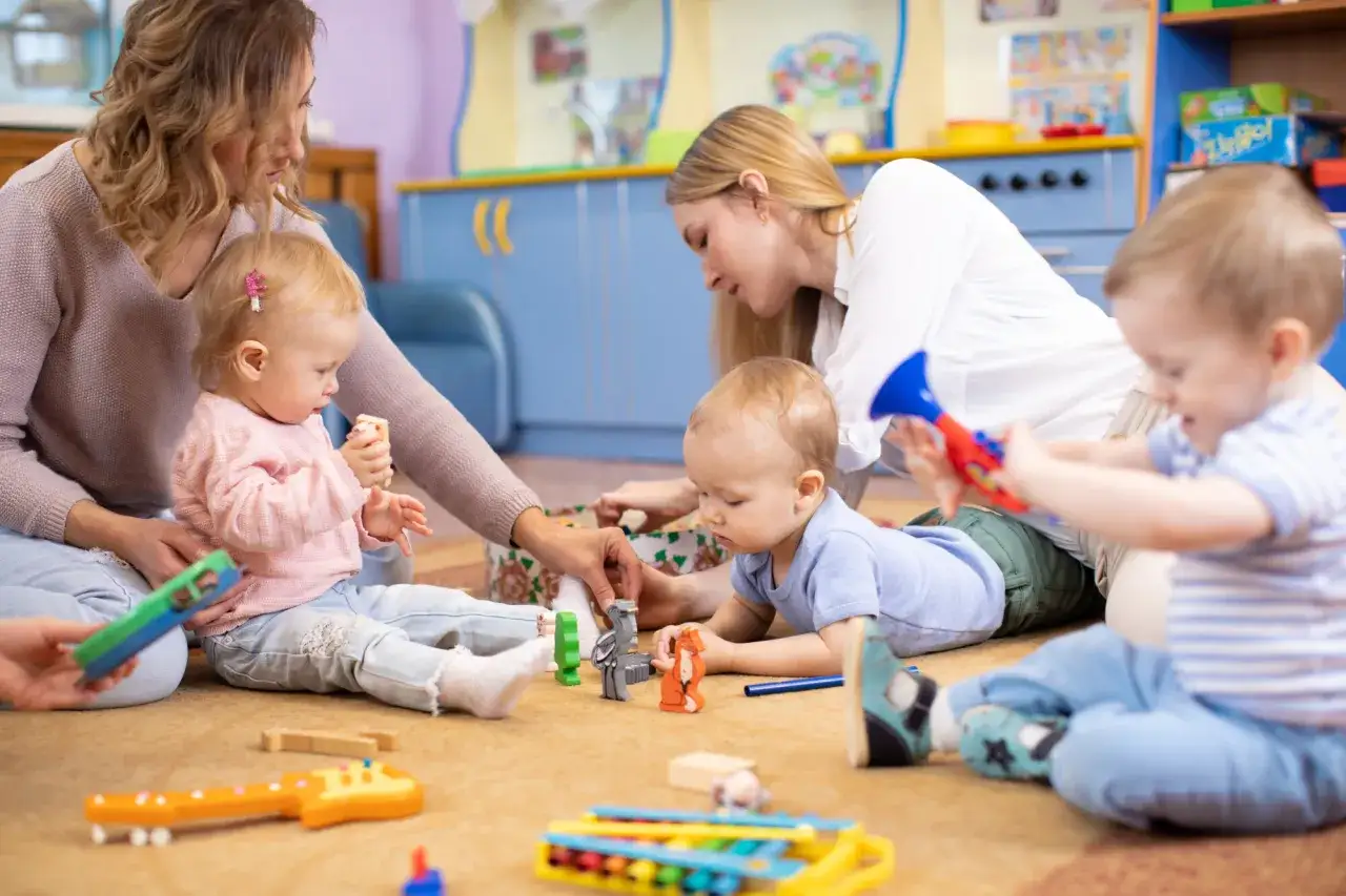 Pomoc opiekuna w żłobku to nie tylko zabawa, ale też rozwijanie umiejętności. Dzieci bawią się zabawkami, a opiekunki czuwają nad ich bezpieczeństwem i rozwojem.