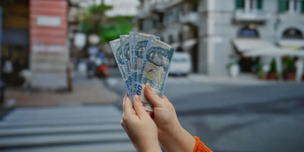 Ręce trzymają banknoty 1000 forintów. Właśnie tyle wynosi waluta w Budapeszcie.