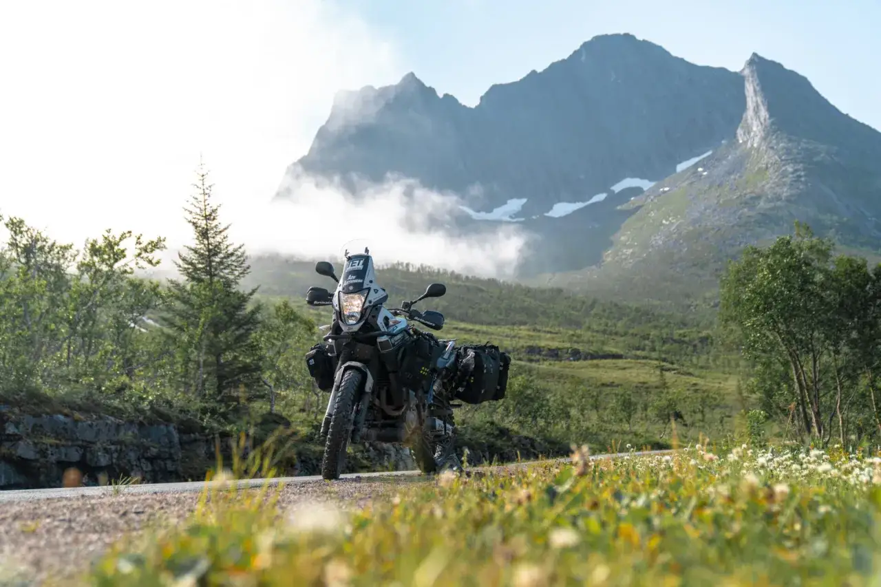Motocykl turystyczny gotowy na przygodę. W tle majestatyczne g&oacute;ry i mgły, idealne miejsce na tankowanie i dalszą podr&oacute;ż. Paliwo w Norwegii to klucz do odkrywania tych krajobraz&oacute;w.
